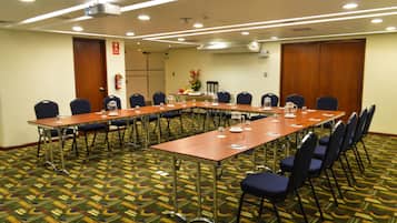 A conference room with a long table, chairs, and a carpeted floor.