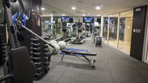 Un gimnasio con cintas de correr, máquinas de pesas y pelotas de ejercicio.