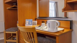 A hotel room with a wooden desk, a chair, a mirror, a tray with a coffee maker, a remote control, and a guest directory. - Best Western Corona (London)