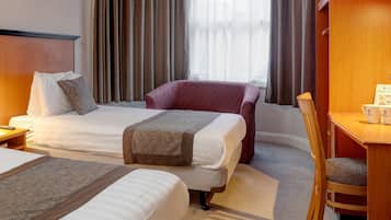 A hotel room with two beds, a desk, and a chair.