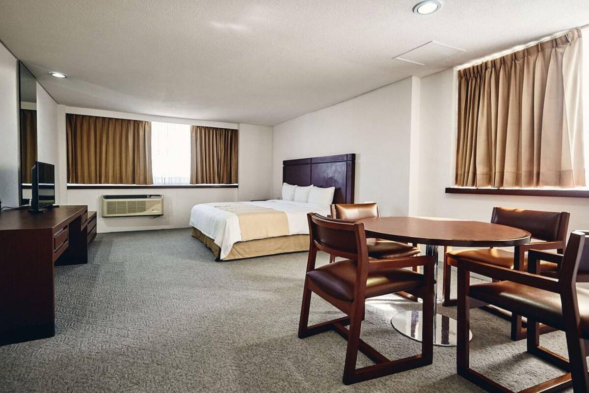 Une chambre d’hôtel équipée d’un lit, d’un bureau, d’une chaise, d’une table et d’un téléviseur.
