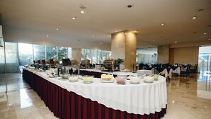 A buffet setup with a variety of food items and a long table covered with a white tablecloth and maroon drapery. - Hotel Del Prado (Mexico City)