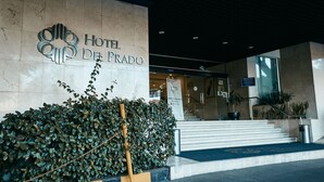The entrance of Hotel Del Prado with a large sign, steps leading up to the entrance, and a well-maintained hedge in front. - Hotel Del Prado (Mexico City)