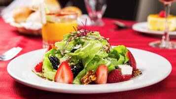 Un plato blanco con una ensalada sobre un mantel rojo.