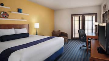 A hotel room with a large bed, a desk with a computer, a chair, and a TV.