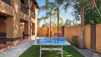 A ping pong table in an outdoor patio area with a building in the background.