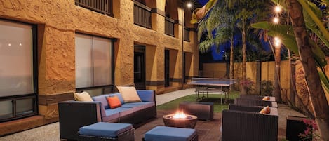 An outdoor patio area with wicker furniture, a fire pit, and a tennis table.