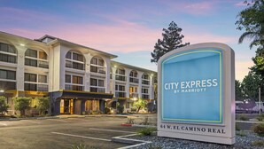 A hotel sign for City Express by Marriott with a clear view of the building's facade and entrance.