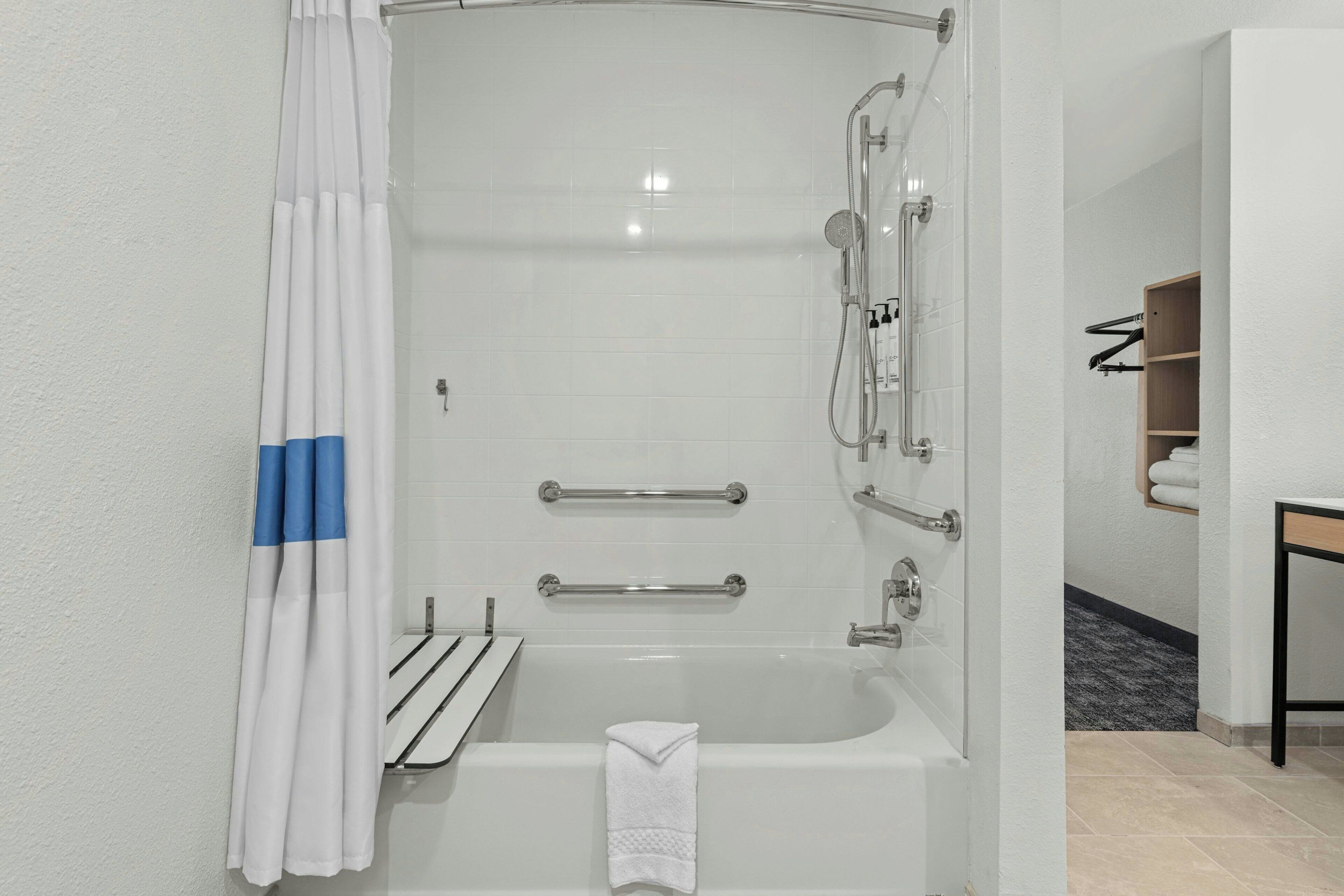 A modern bathroom with a bathtub, shower, and grab bars.