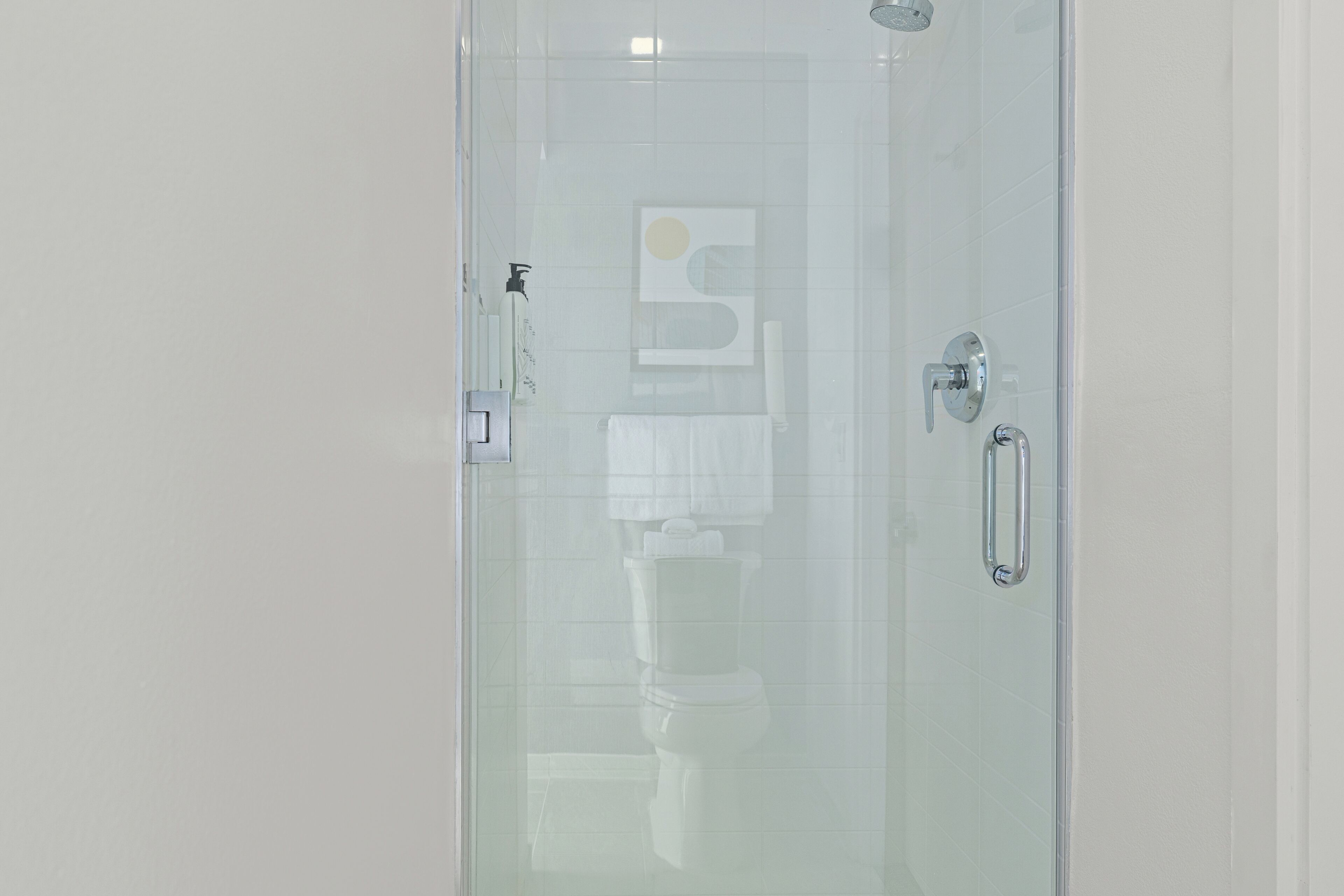 A bathroom with a glass shower enclosure, a toilet, and a towel rack.