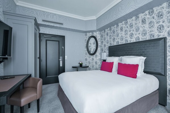 Une chambre d’hôtel avec un grand lit, un bureau, une chaise et un téléviseur.