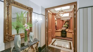 A hallway with a large ornate mirror, a vase with flowers, and a marble console table. - Maison Astor Paris, Curio Collection by Hilton (Paris)