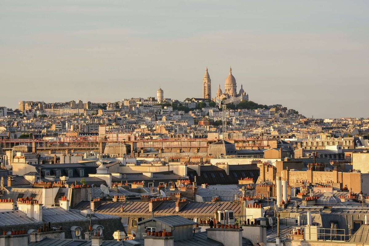 A cityscape with densely packed buildings, a prominent dome structure in the distance, and a mix of residential and commercial architecture.
