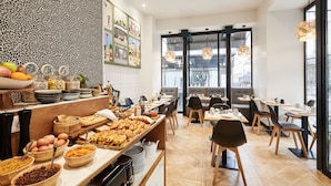 A breakfast buffet with various food items and a modern interior design. - Hôtel Petit Lafayette (Paris)