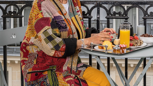 A person sitting at an outdoor table with a tray of breakfast items, including toast, fruit, and a beverage. - Hôtel Petit Lafayette (Paris)