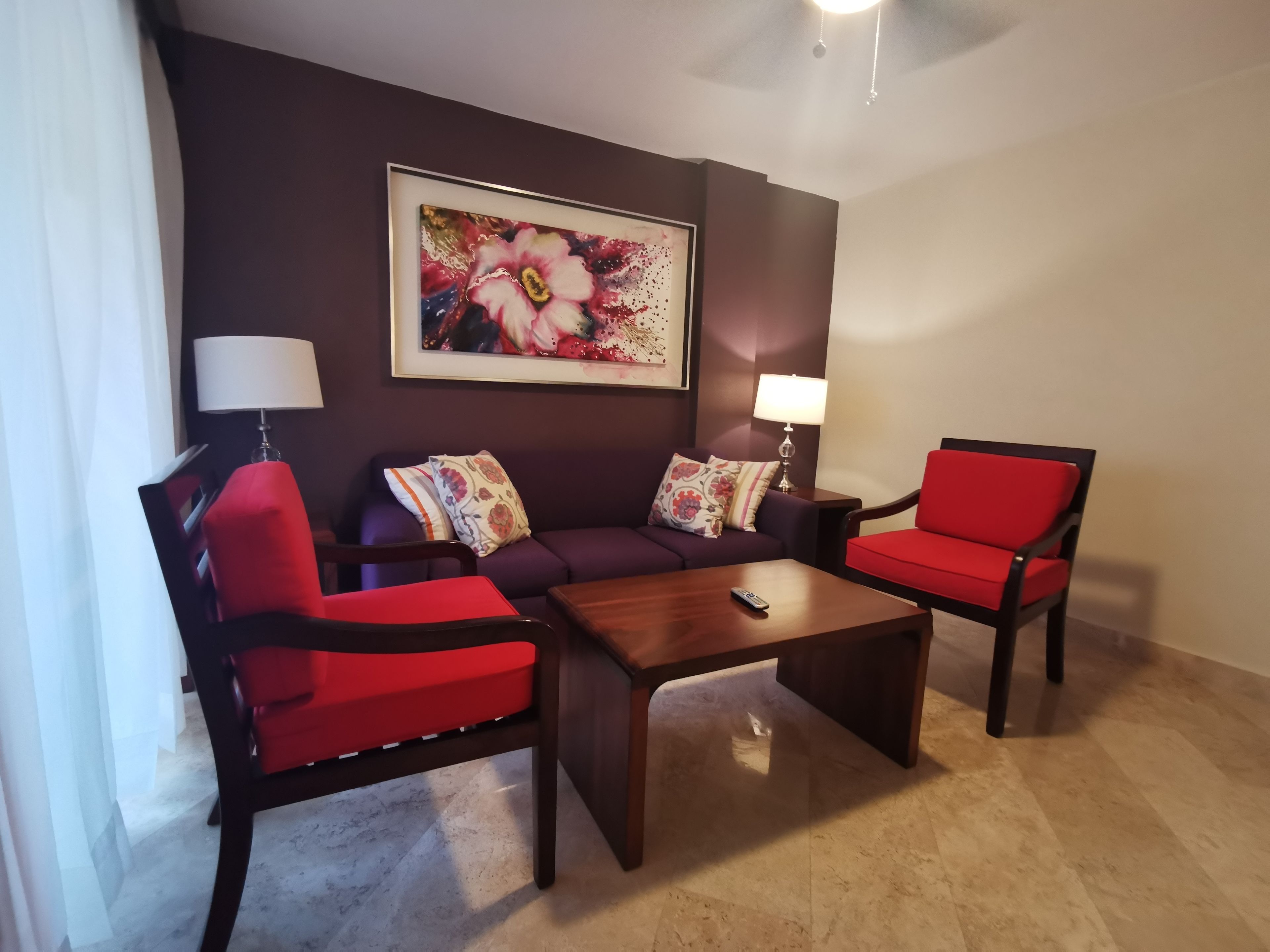 A living room with a sofa, two armchairs, a coffee table, and a wall-mounted painting.