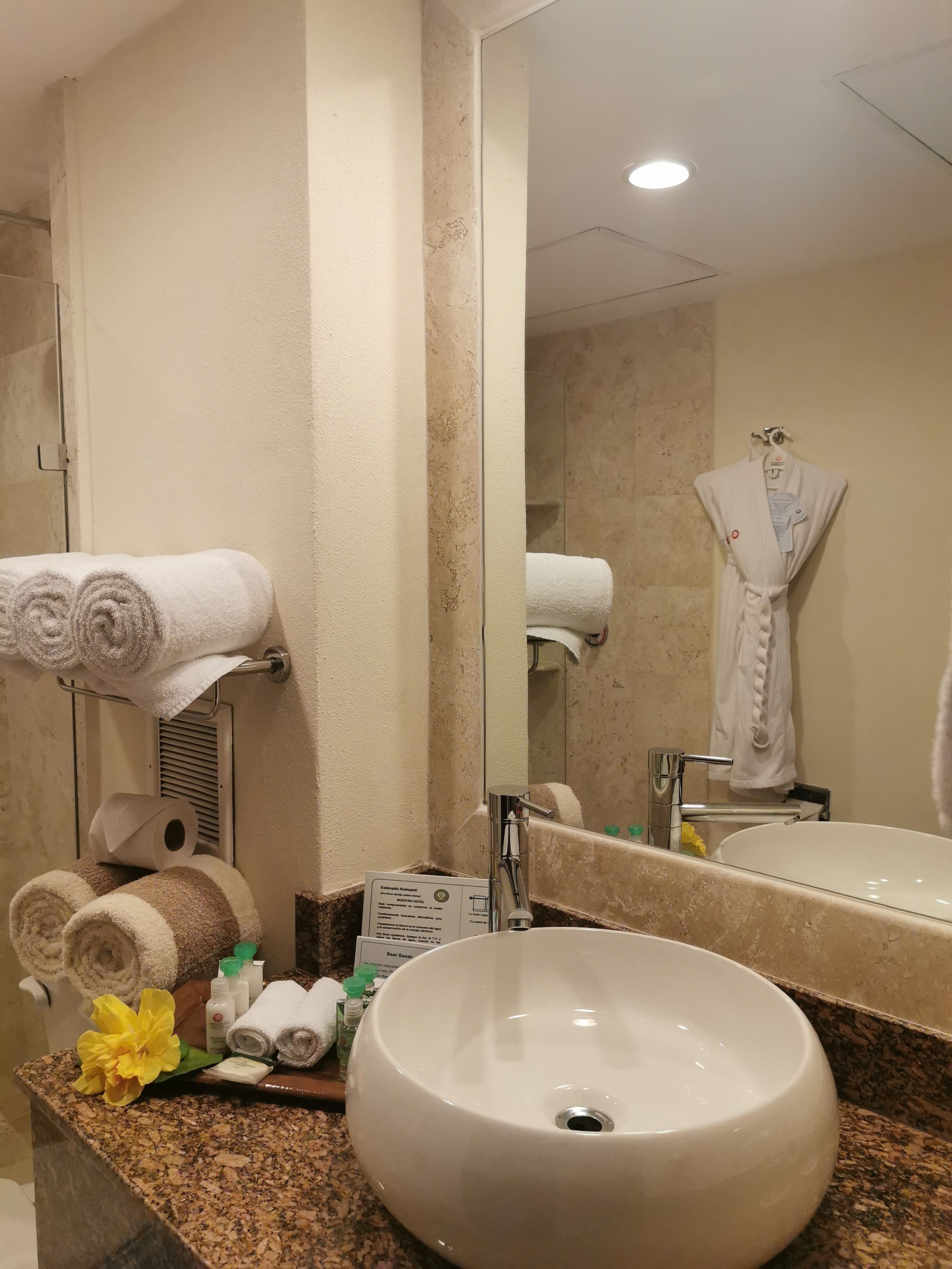A bathroom with a large mirror, a sink, and towels on a rack.
