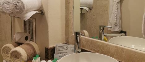 A bathroom with a large mirror, a sink, and towels on a rack.