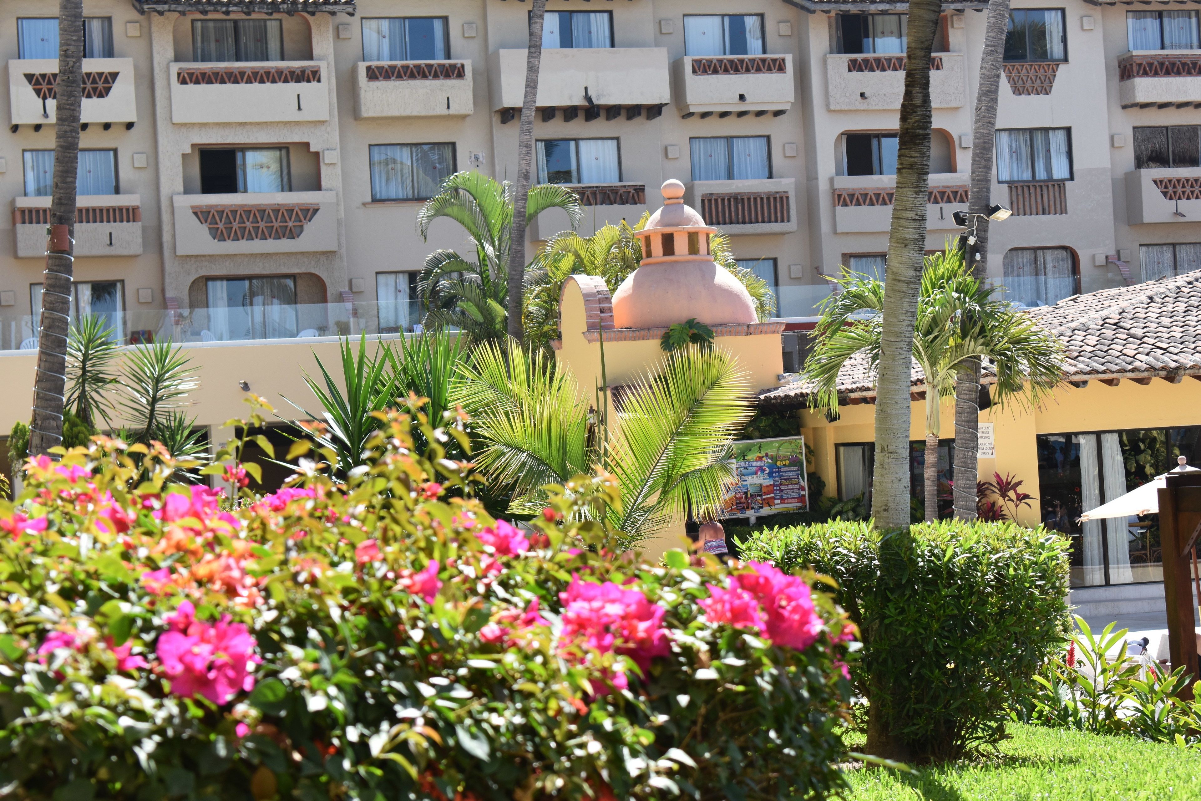 A hotel with a central courtyard, palm trees, and a building with balconies.