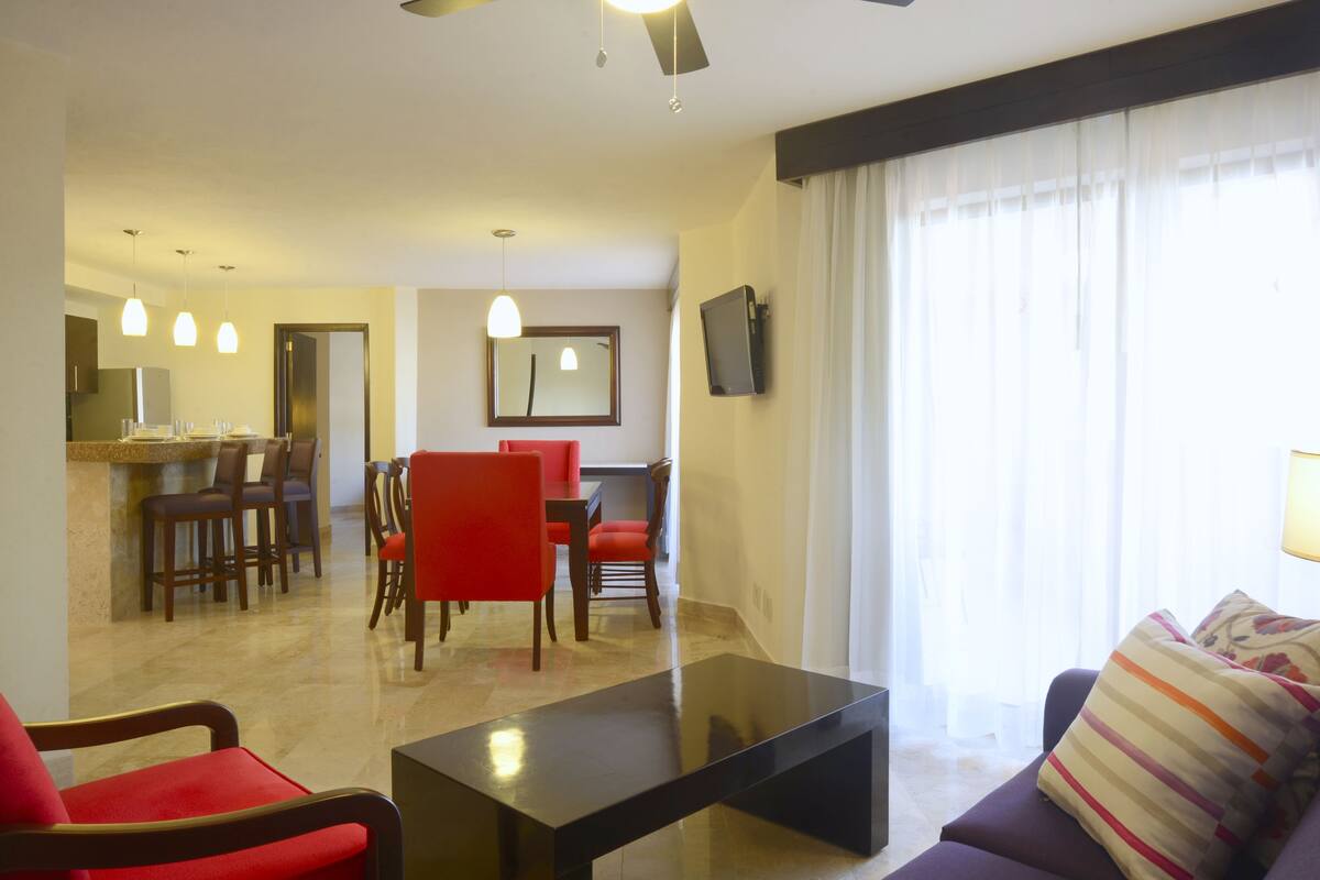 A modern living room with a sofa, a coffee table, and a dining area with chairs and a table.