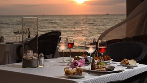A table set for a meal with a sunset view, glasses of red wine, and a candle. - Canto del Sol Puerto Vallarta All Inclusive (Puerto Vallarta)