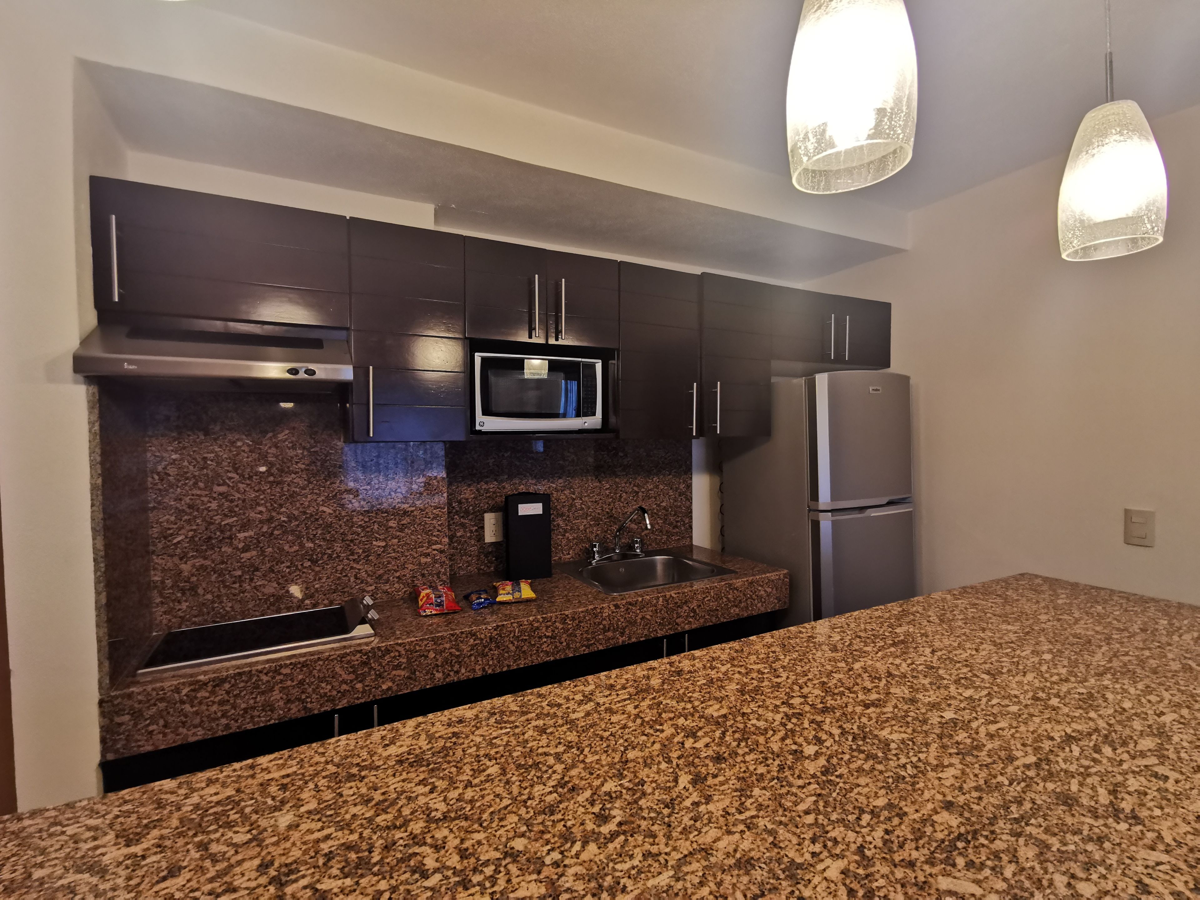 A modern kitchen with granite countertops, stainless steel appliances, and pendant lighting.