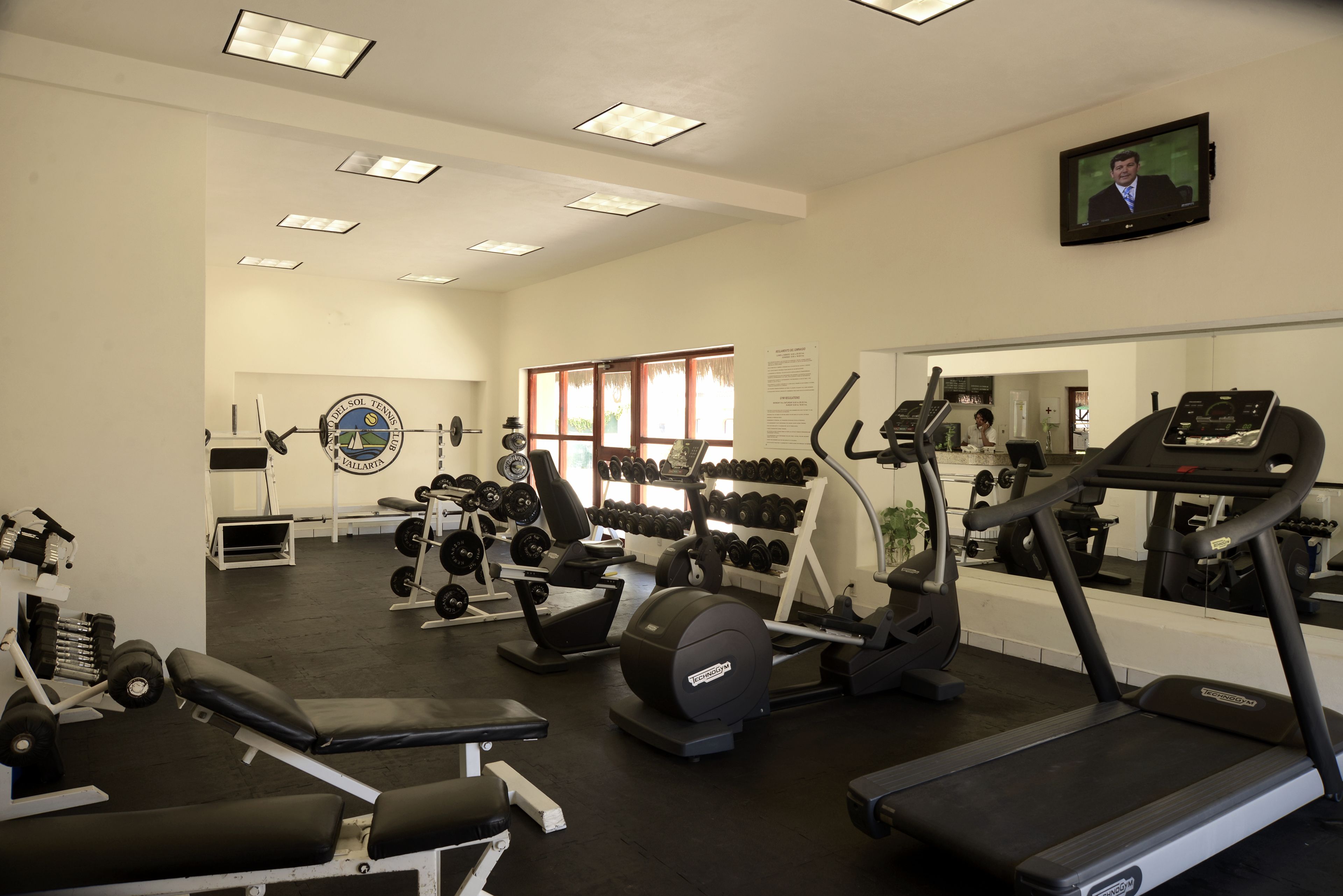 A gym with treadmills, weight machines, and dumbbells.
