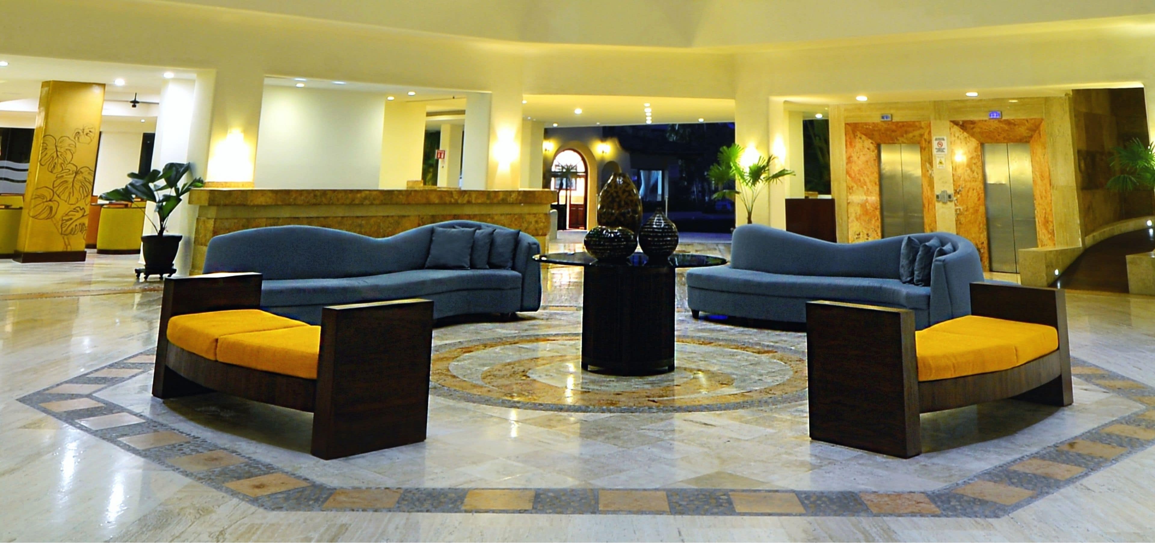 A spacious lobby with two sofas and a central coffee table, featuring a marble floor and a decorative circular pattern.