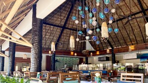A restaurant with a thatched roof, hanging decorative lights, and a view of fish through the glass wall. - Canto del Sol Puerto Vallarta All Inclusive (Puerto Vallarta)
