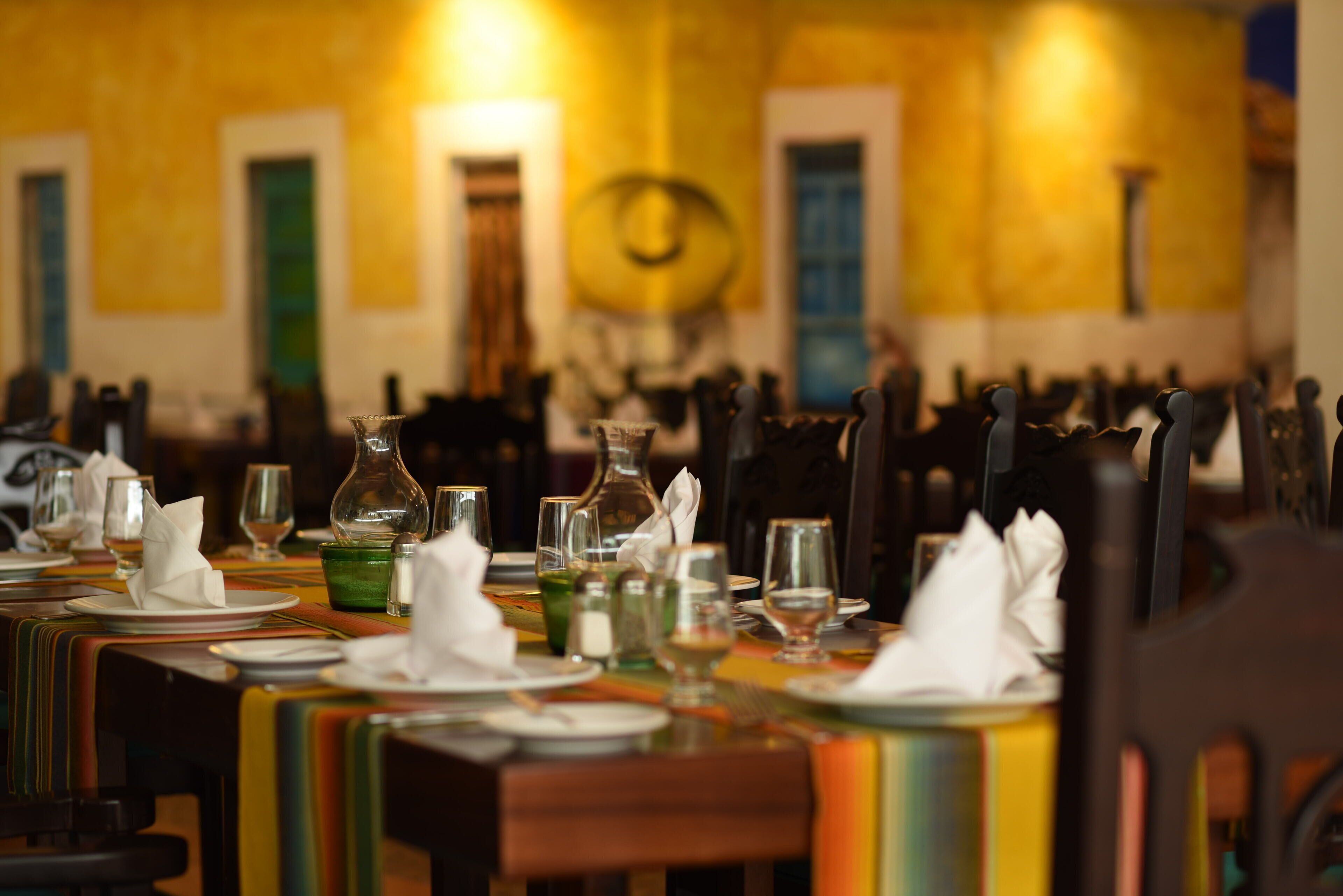 A dining area with tables set for a meal, chairs, and a variety of tableware.