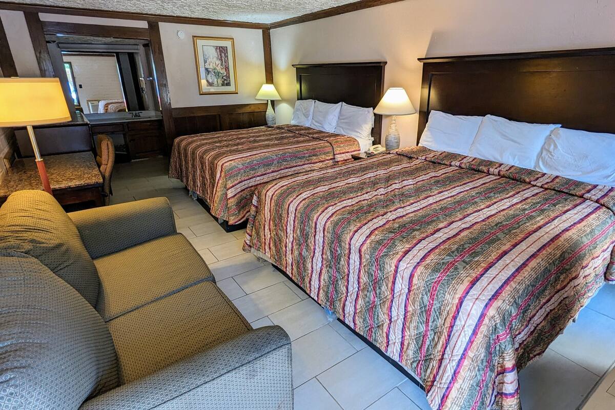 Ein Hotelzimmer mit zwei Betten, einem Sofa und einem Schreibtisch.