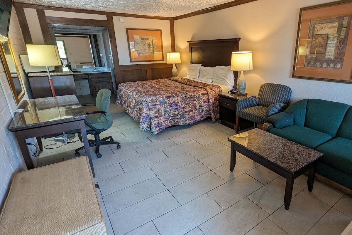 Ein Hotelzimmer mit Bett, Sofa, Schreibtisch, Stuhl und einem kleinen Tisch.