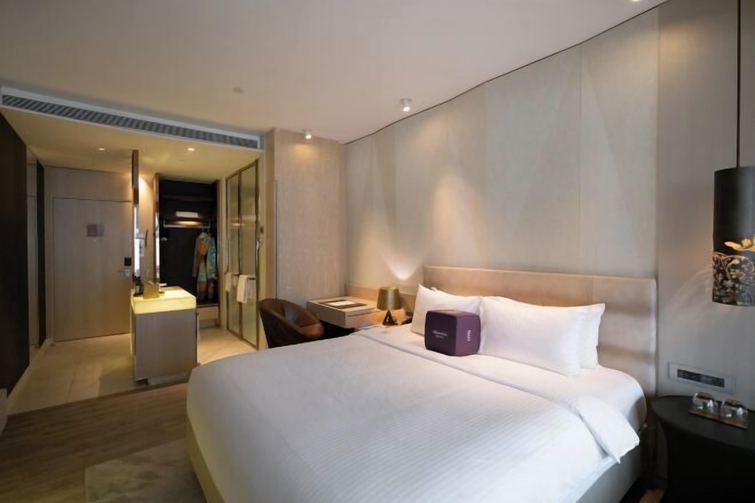 A hotel room with a large bed, bedside tables, a mirror, and a wardrobe.