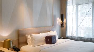 A hotel room with a bed, bedside table, lamp, and a window with a view.