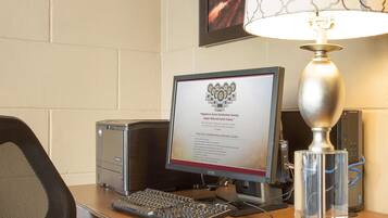 Ein Hotel-Schreibtisch mit einem Desktop-Computer, einer Tastatur, einer Maus und einem gerahmten Zertifikat auf dem Bildschirm.