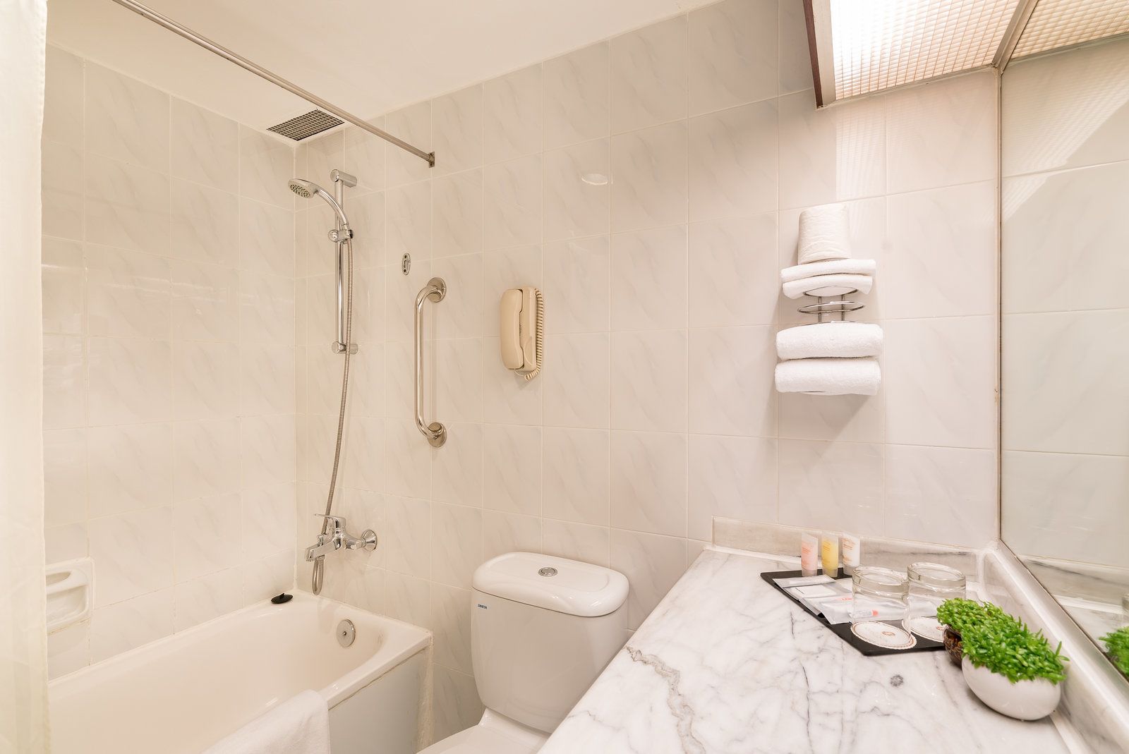 A modern bathroom with a bathtub, toilet, and shower.