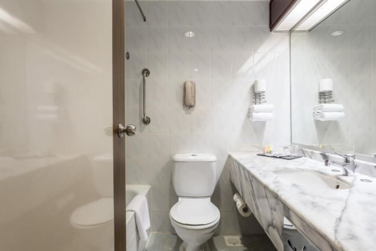 A modern bathroom with a toilet, a sink, and a mirror.