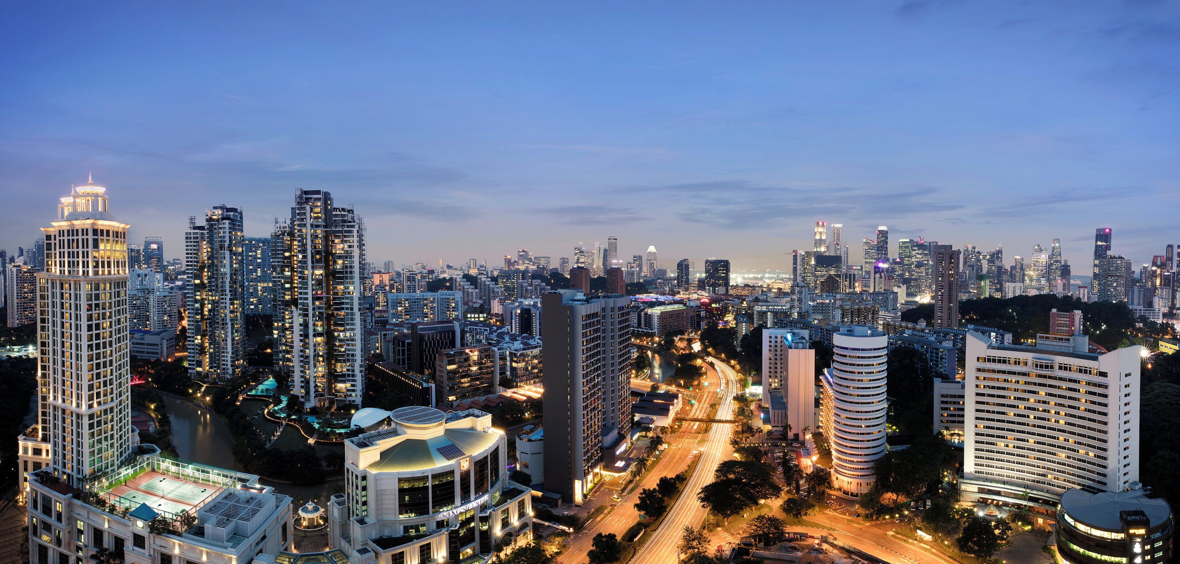 A high-rise hotel with multiple floors, a rooftop pool, and a cityscape view.