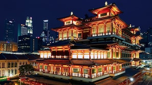 A traditional multi-tiered building with illuminated railings, set against a modern city skyline at night. - Holiday Inn Singapore Atrium by IHG (Singapore)