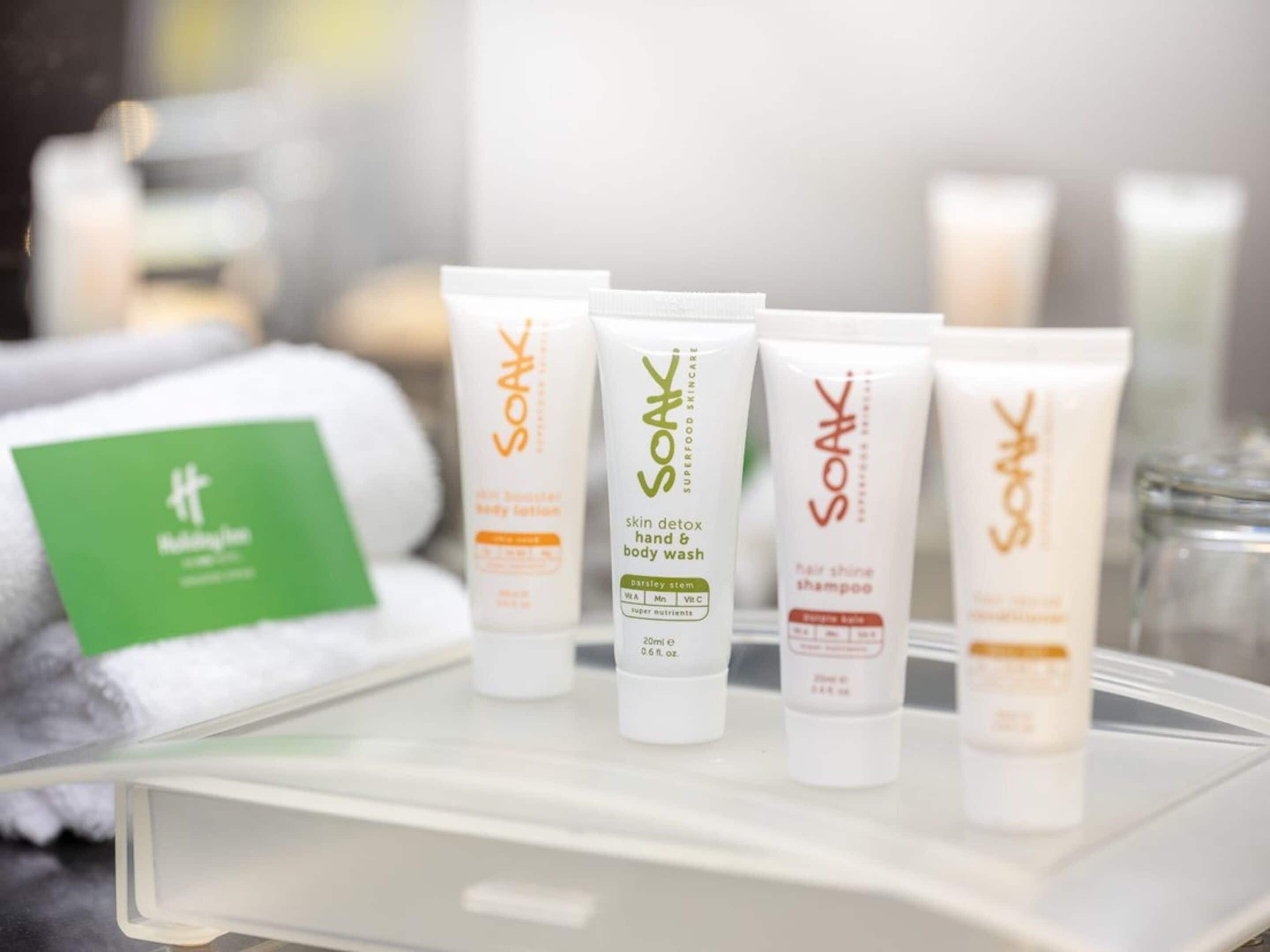 Uma bandeja com diversos produtos de cuidados da Soak, incluindo loção corporal, sabonete líquido para mãos e corpo e shampoo para brilho do cabelo.