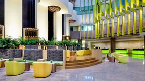 A spacious lobby with a modern design, featuring a central seating area with sofas and a staircase leading to upper levels. - Holiday Inn Singapore Atrium by IHG (Singapore)
