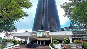 A modern hotel entrance with a glass facade, a fountain, and a landscaped area with steps leading up to the entrance. - Holiday Inn Singapore Atrium by IHG (Singapore)