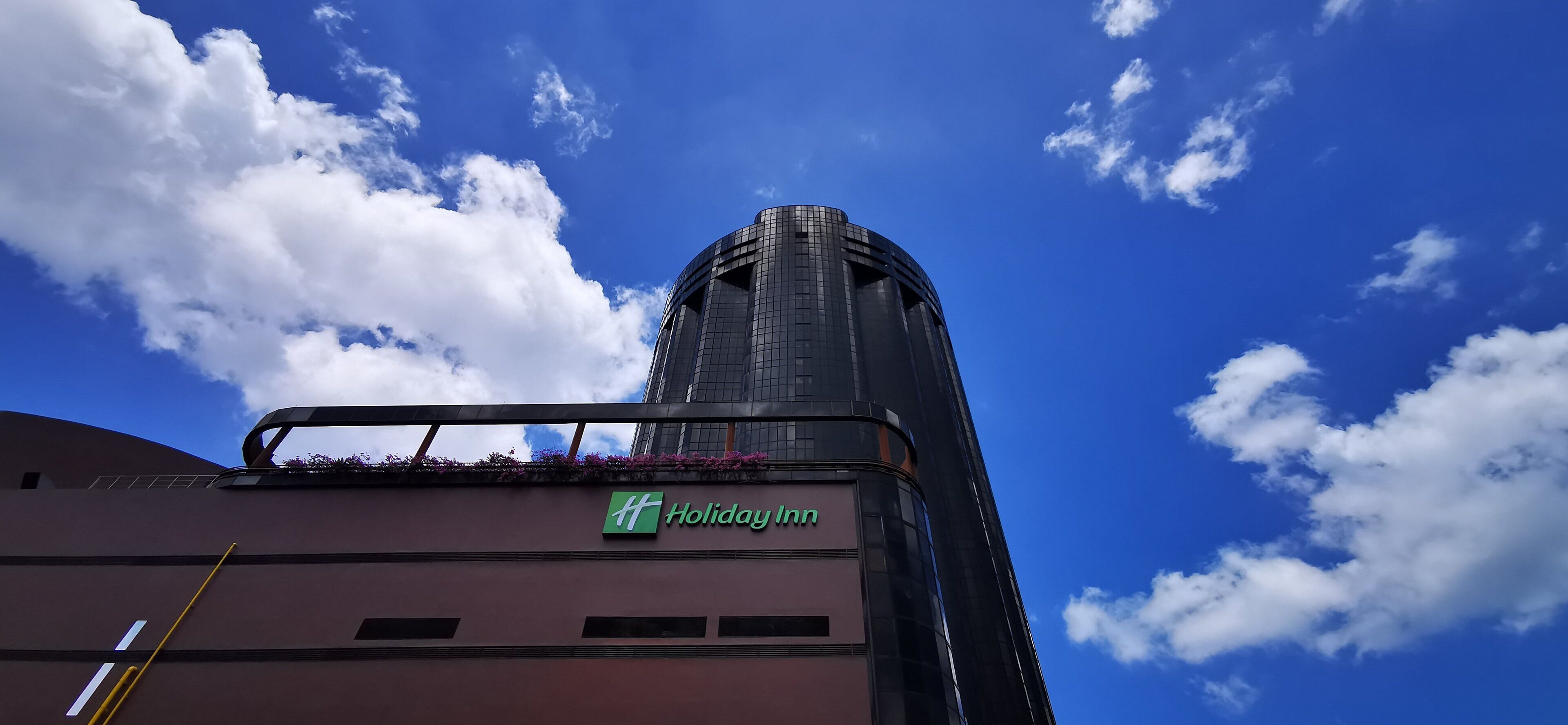 Un edificio Holiday Inn con un cielo azul despejado y nubes al fondo.