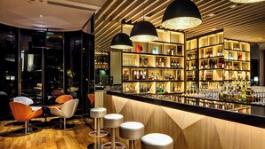 A bar area with stools, a counter, and shelves of bottles. - Holiday Inn Singapore Atrium by IHG (Singapore)