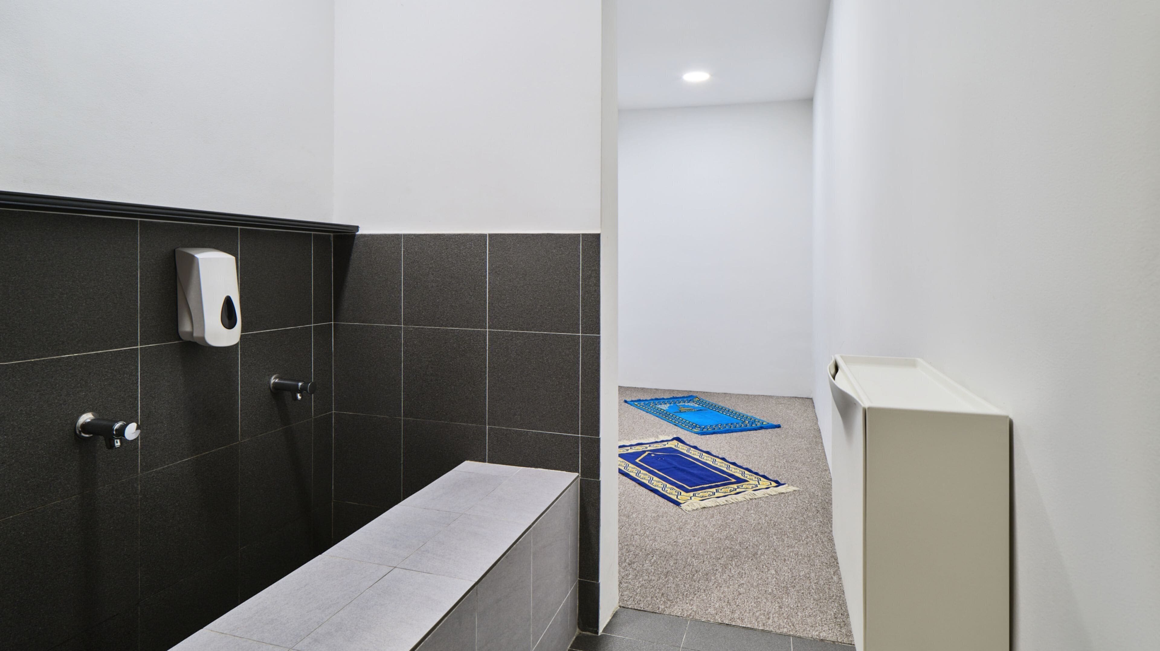 A modern bathroom with a hand dryer, a towel rack, and a small bench.