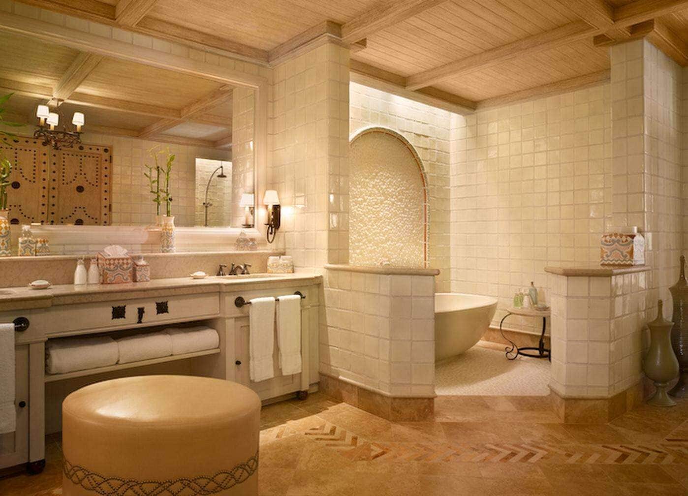 Un baño con bañera, un espejo grande, un tocador con lavabo y un perchero para toallas.