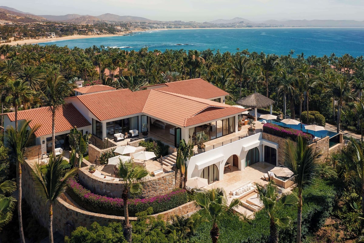 A coastal property with a large house, a pool, and a view of the ocean.