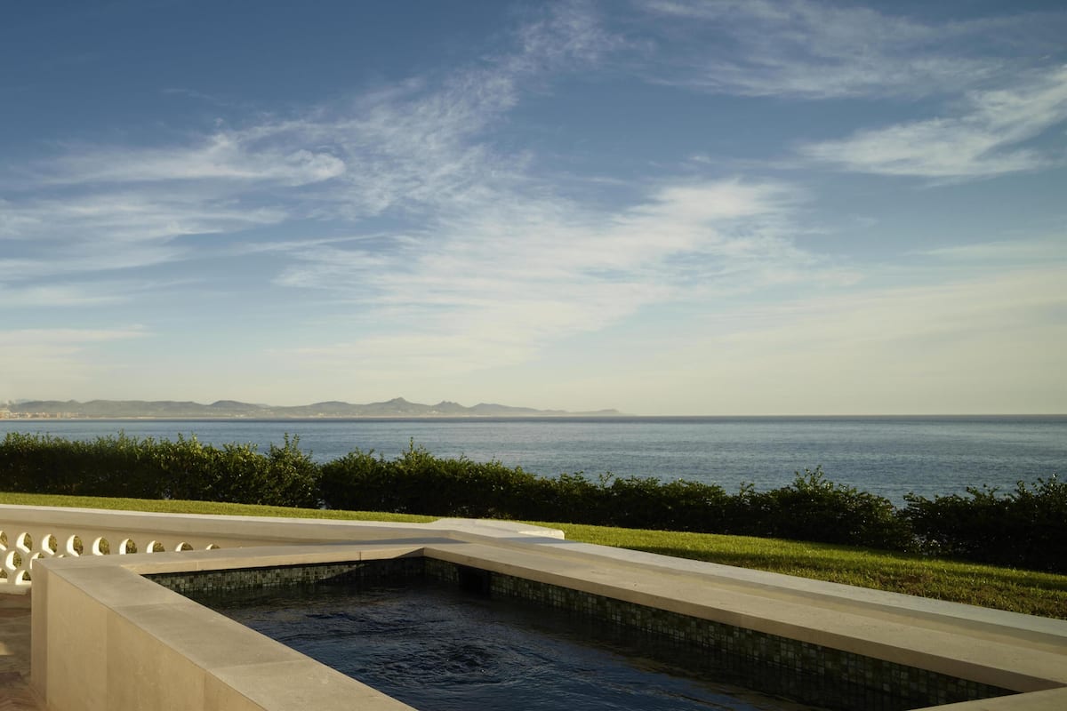 A swimming pool with a view of the sea and distant mountains.