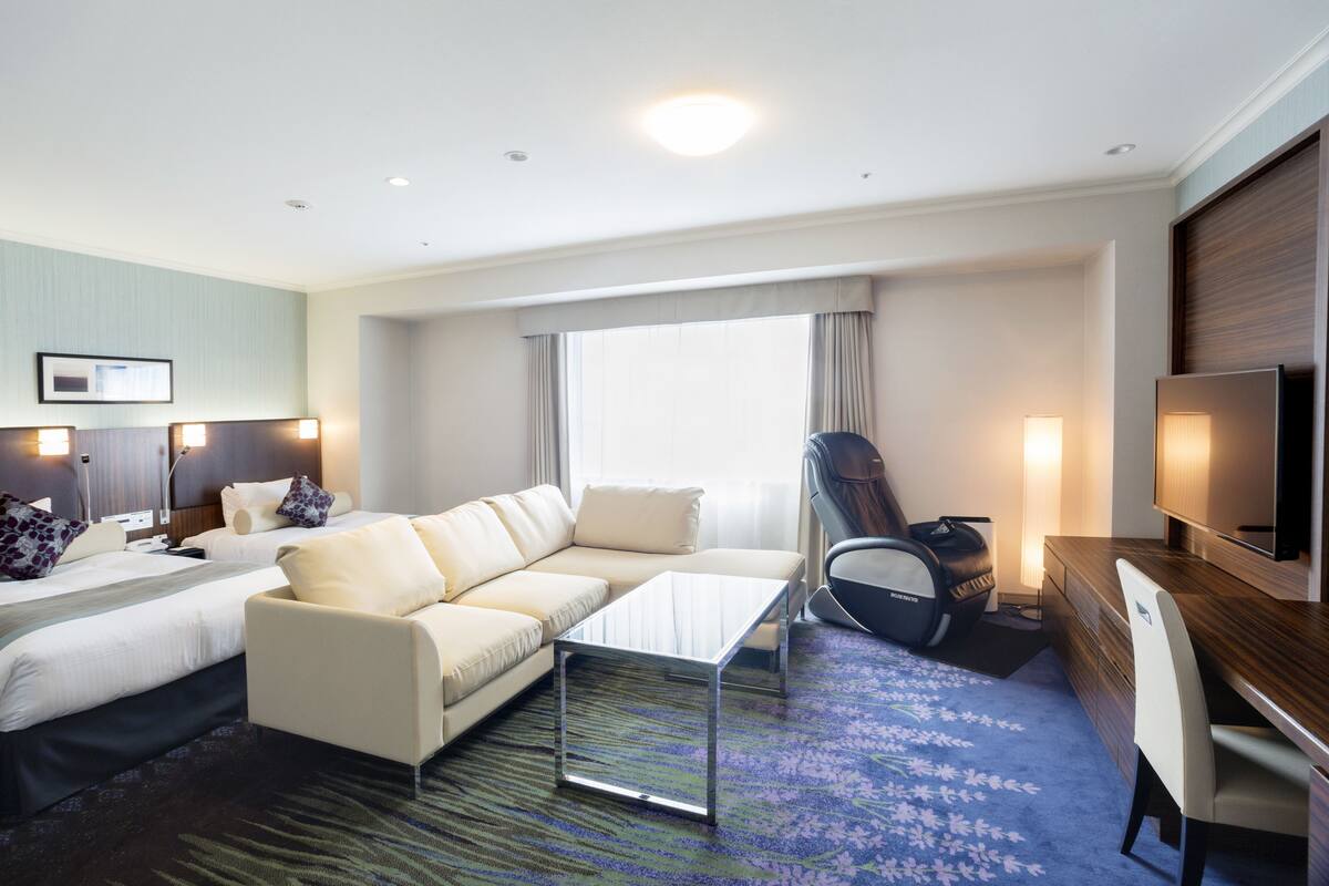 Ein Hotelzimmer mit einem Bett, einer Couch, einem Schreibtisch und einem Fernseher.