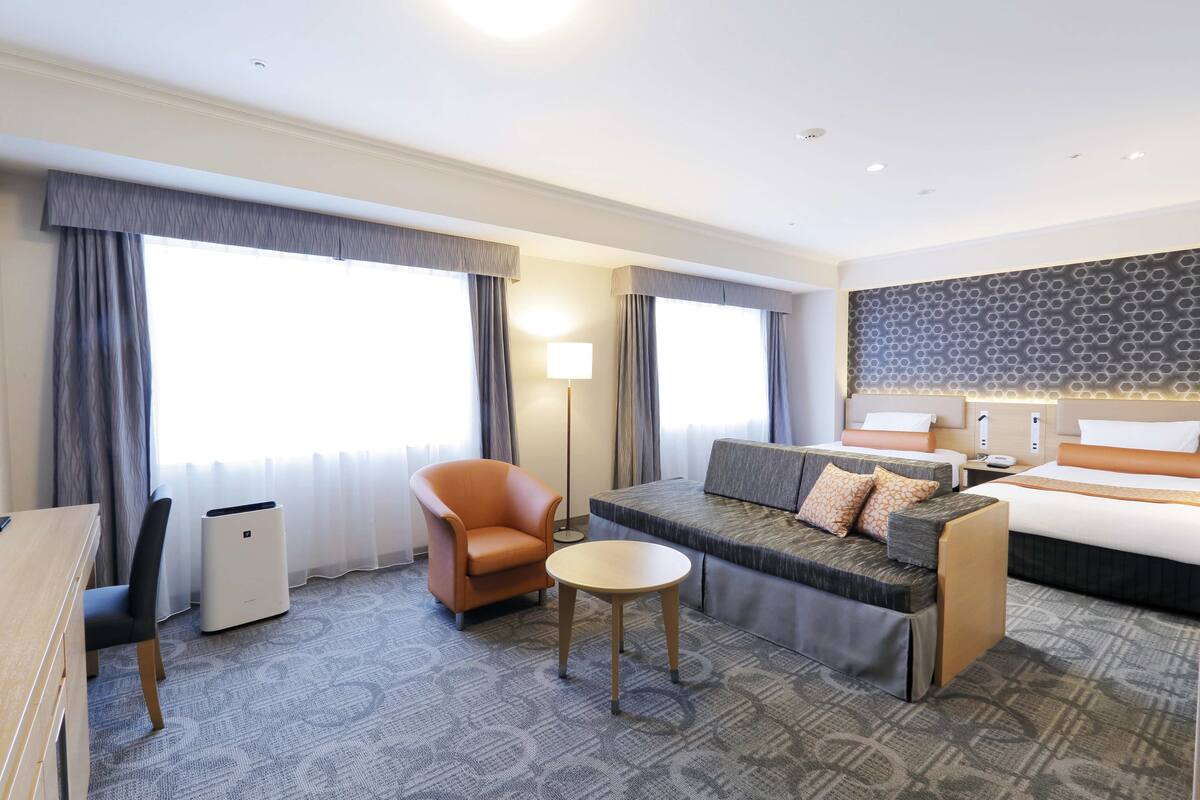Ein Hotelzimmer mit Sofa, Sessel, kleinem Tisch und Bett.